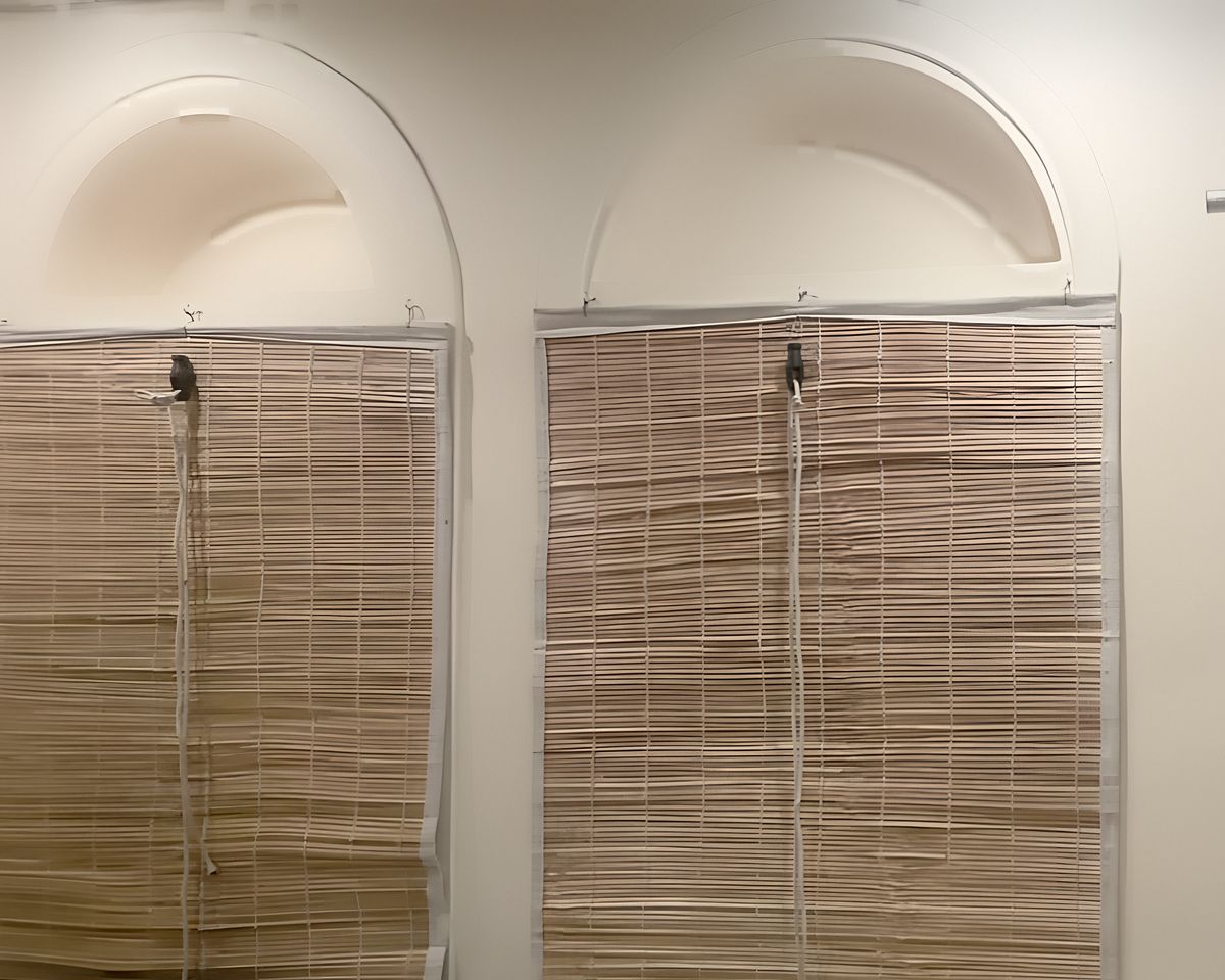 Two arched windows with bamboo blinds set into the plastered walls of the haveli